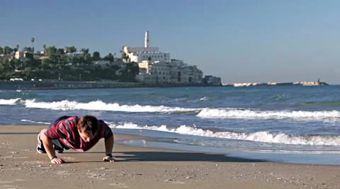 A young man is pushing up on the beach with the castle in the background. Color Stock Footage 57977129