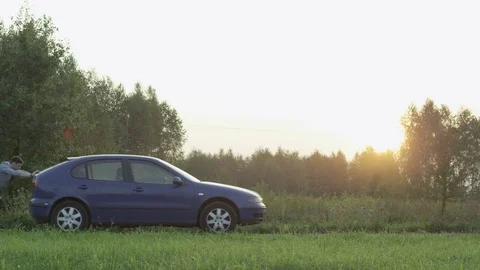Young Man Pushing the Car Seen From the Side. Sunset Stock Footage