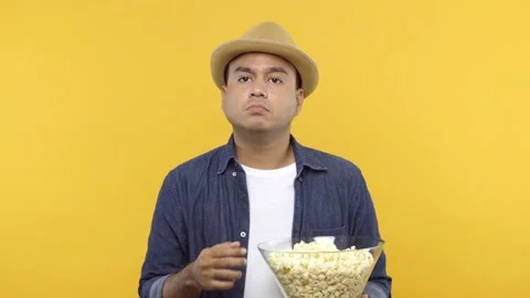 A young man put on hat eats popcorn while watching something scary isolated on y Stock Footage 144662733