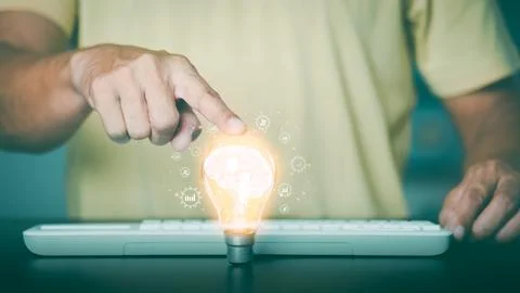 The young man put his hand on the light bulb on the table. Stock Photos