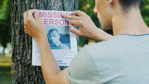 A young man puts up ads for a missing person in the park Stock Footage 109446187