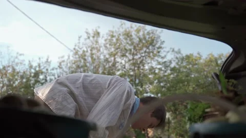 The young man puts the buckets and the bag of vegetables in the trunk of the car Stock-Footage 194544858
