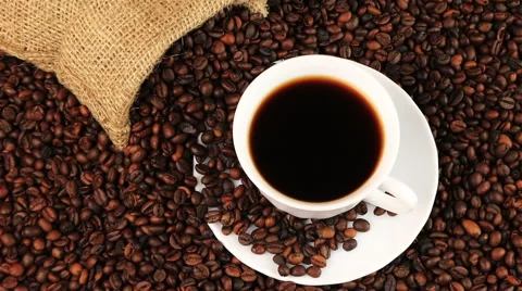 Young man puts a cup of black coffee with roasting coffee beans background Stock Footage 65235836