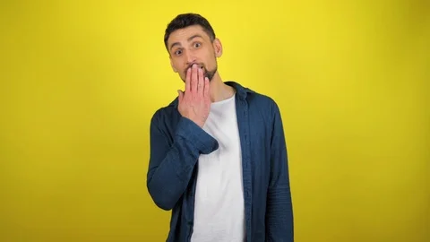 A young man puts his hand to his lips and looks at the camera Video stock 119858979