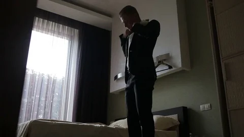 Young man  puts on his jacket in light room. Stock Footage 70624972