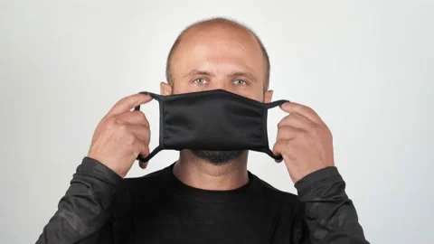 A young man puts on a mask and looks at the camera. Vídeo Stock 133577904