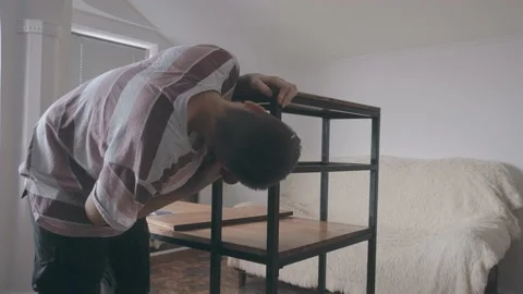 A young man puts a self-tapping screw on a screwdriver and screw it Vidéo 145182366