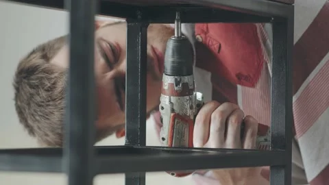 A young man puts a self-tapping screw on a screwdriver 库存影片 145182624