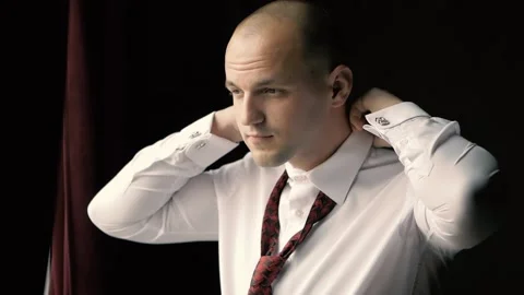 A young man puts on a tie, a man in a white shirt stands by the window Stock Footage 162372541