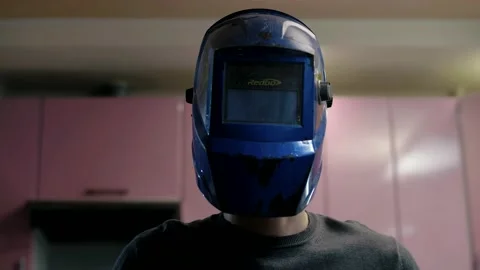 Young man putting on a blue welding helmet Stock Footage 151646780