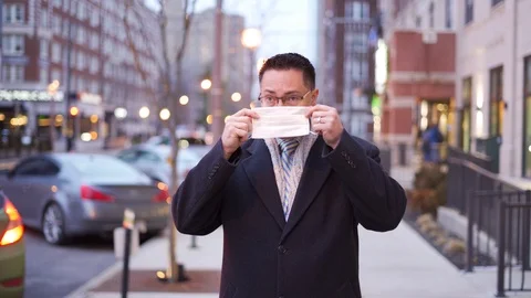 Young man putting on face mask in city downtown Video stock 124981337