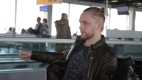 Young man is putting on headphones while sitting at airport. Stock Footage 83192152