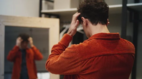 Young man putting on jacket at home, focused on his appearance before leaving Stock Footage 337908176