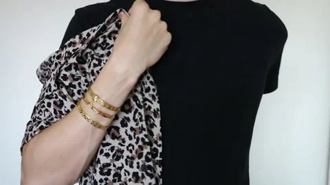 Young man putting on leopard print shirt, wearing gold color bracelets, black t- Stock Footage 137210507