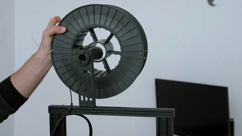 Young man putting new spool with grey filament on 3d printer. Stock Footage 131099717