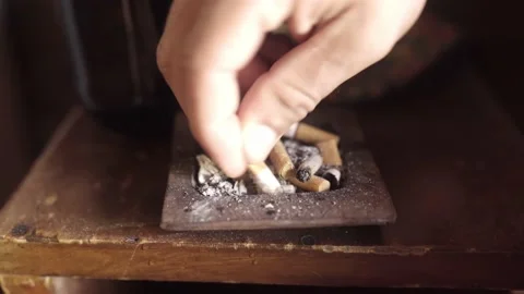 A young man is putting out a cigarette in an ashtray Stock Footage 221786481