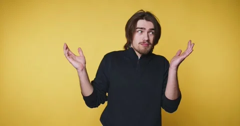 Young man with a puzzled expression raises his hands, symbolizing confusion.. Stock Footage 314336995
