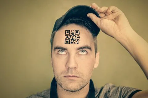 Young man with a qr code on his forehead. A man with a stupid expression look Stockfoto's