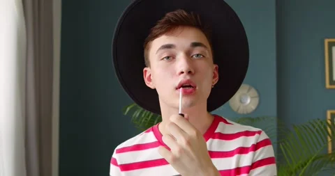 Young man queer doing makeup lipstick or lip gloss and paints lips Stock Footage 135532934
