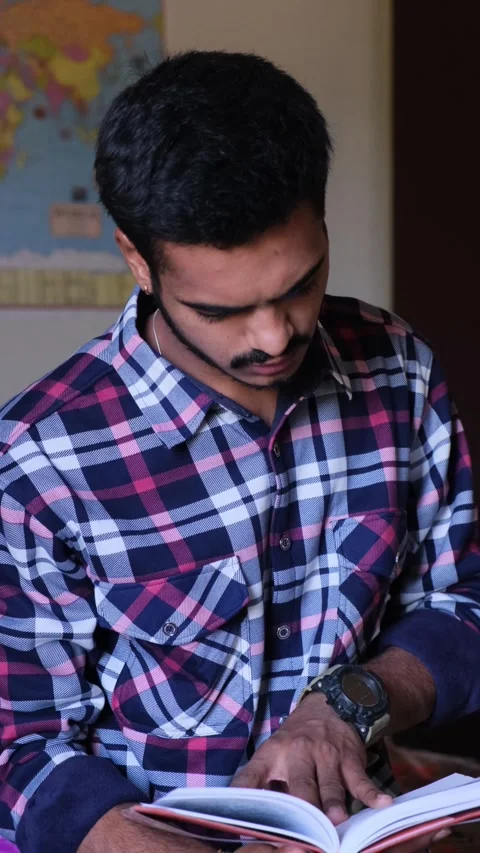 Young man quickly flipping pages of a book to find information Видео 331354382