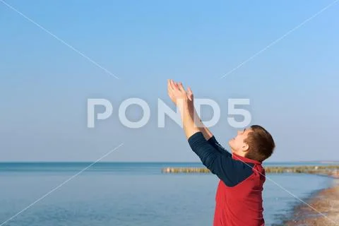 The young man raises his hands up, the young man raised his hands to the sun on Stock Photos