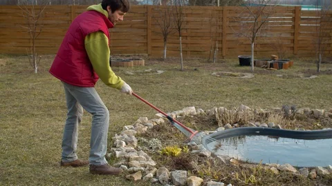 Young man raking dry grass Stock Footage 128790099