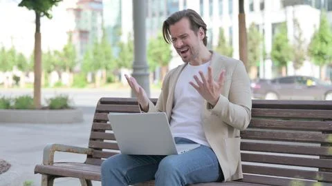 Young Man Reacting to Loss on Laptop while Sitting on Bench Stock Photos