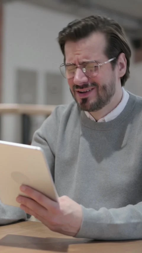 Young Man Reacting to Loss on Tablet while Sitting in Office, Vertical Video Vídeo Stock 339580991