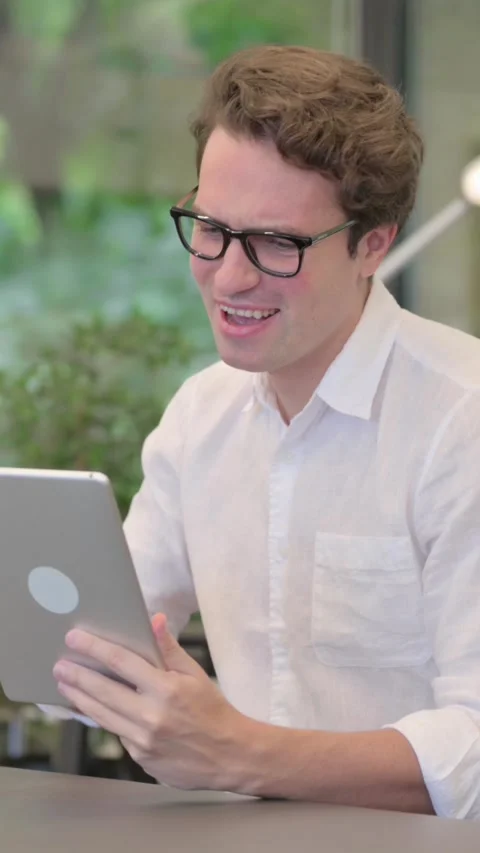 Young Man Reacting to Loss on Tablet while Sitting in Modern Office, Vertical Stock Footage 340032464