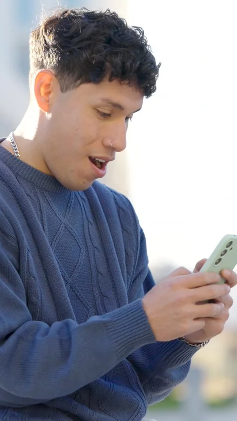 Young man reacting to smartphone content in split screen. Vertical Stock Footage 304891634