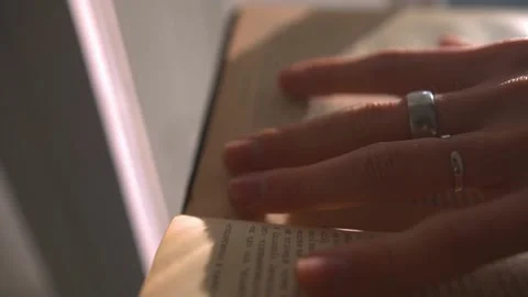 A young man reading aged pages of an ancient book in a dark university library 스톡 동영상 198026839