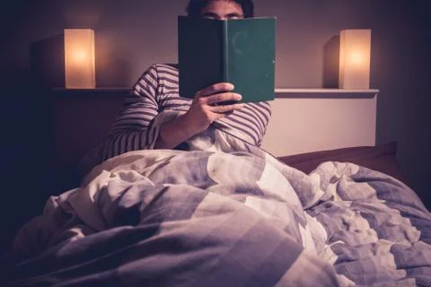 Young man is reading in bed 스톡 사진