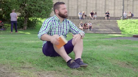 Young man reading book and relax, sitting on grass. Steadicam. 库存影片 67237764