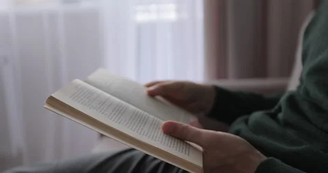 Young man reading a book and turning pages, close up. Male hands holding a book Stock Footage 221925816