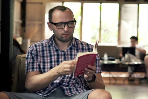 Young man reading book in cafe NTSC Stock Footage 51433538