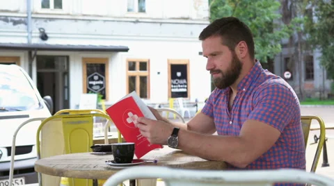 Young man reading book in cafe 库存影片 67633258