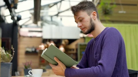 Young man reading book in the cafe and drinking coffee, steadycam shot 스톡 동영상 70700473