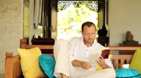 Young man reading book on comfortable sofa at home  HD 스톡 동영상 40828280