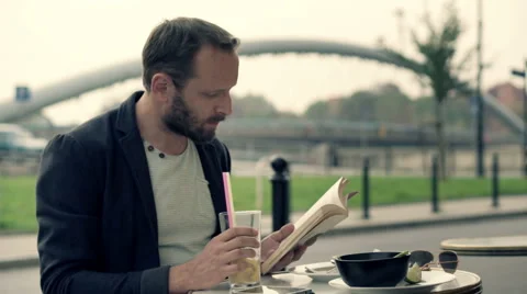 Young man reading book drinking cocktail in street cafe HD Stock Footage 55648720