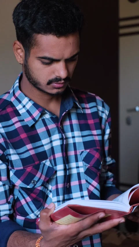 Young man reading a book with focus and concentration Vidéo 331354498