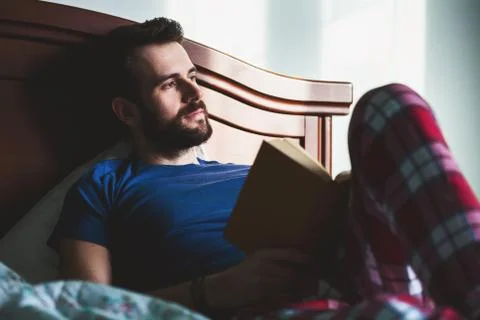 Young man reading a book in his bedroom Stock Photos