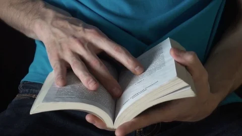 Young man reading a book, leafing through pages,slow motion Stock-Footage 77082573
