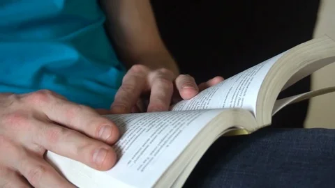 Young man reading a book, leafing through pages,slow motion Видео 77085664