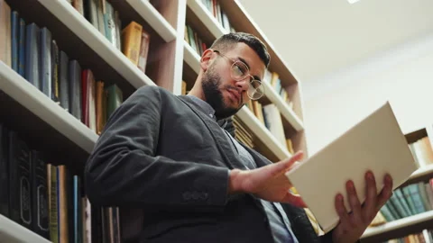 Young man reading book in library Stock Footage 203743465