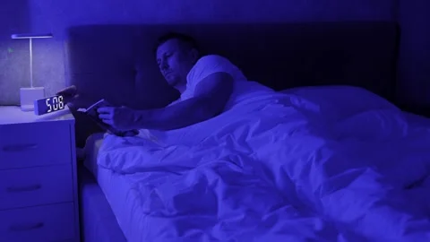 Young man reading book lying in bed, early in the morning. Insomnia and peo.. Stock Footage 290309155