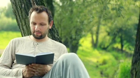 Young man reading book in the park Stock Footage 8579738