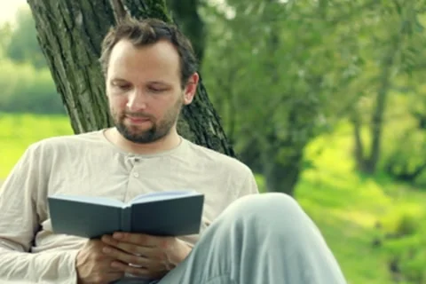 Young man reading book in the park Stock Footage 8579743