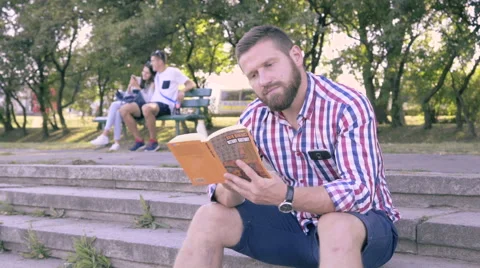 Young man reading book, sitting on stairs. Vidéo 67244973