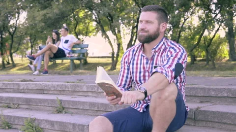 Young man reading book, sitting on stairs. Vídeo Stock 67245331