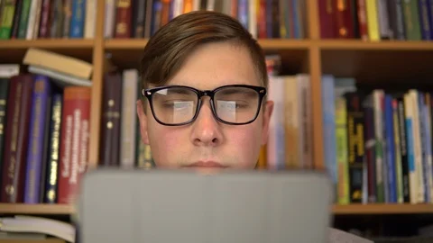 A young man is reading a book in a tablet. A man with glasses carefully looks at Stock Footage 121532835